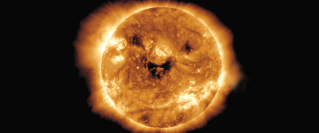 The Sun showing bright orange surface with dark sunspots and glowing corona